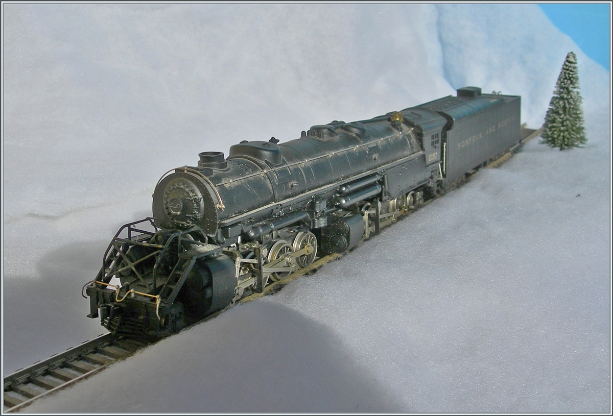 The Mallet steam locomotive 2-8-8-2 - Y6b 2197 of the Norfolk & Western, which is powerful even in H0, fights its way through the snow. The design of the Mallet model locomotives is based on information provided by the U.S.R.A. (United States Raitroad Administration) introduced during the First World War. The class Y6b locomotives were delivered from 1936. Basically, the Y6b class was designed to pull heavy freight trains at 30 mph, but in good conditions up to 50 mph could be achieved. 

The model of this articulated locomotive type Mallet “Y 6 b” from the “Norfolk & Western” is probably a good 50 to 60 years old and is a very impressive model implementation in terms of size. It doesn't seem entirely logical to me why the engine was squeezed into the driver's cab with so much space in order to then drive the distant  bogies  using long cardan shafts. The tender is prototypically equipped with two three-axle  Buckeye  bogies, which are also used to collect power. 

The model probably hasn't been driven for a good twenty to thirty years. After I dismantled the model and degreased and re-oiled the moving parts, it has been running again since yesterday, even if I have both the cars and the route for the discontinuation of the mighty model missing. 

Jan 12, 2025 
