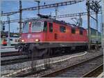 The SBB Re 4/4 II 11263 (Re 420 263-6), which is equipped with a Scharfenberg type automatic coupling, is waiting in Lausanne with a freight train that also has automatic couplings for the onward journey to St-Triphon. Actually, the buffers would no longer be necessary with the automatic coupling (the wagons, for example, no longer have any), but the automatic coupling of the Re 420 can be turned away if necessary and the locomotive can run with the usual coupling. 

March 8, 2025